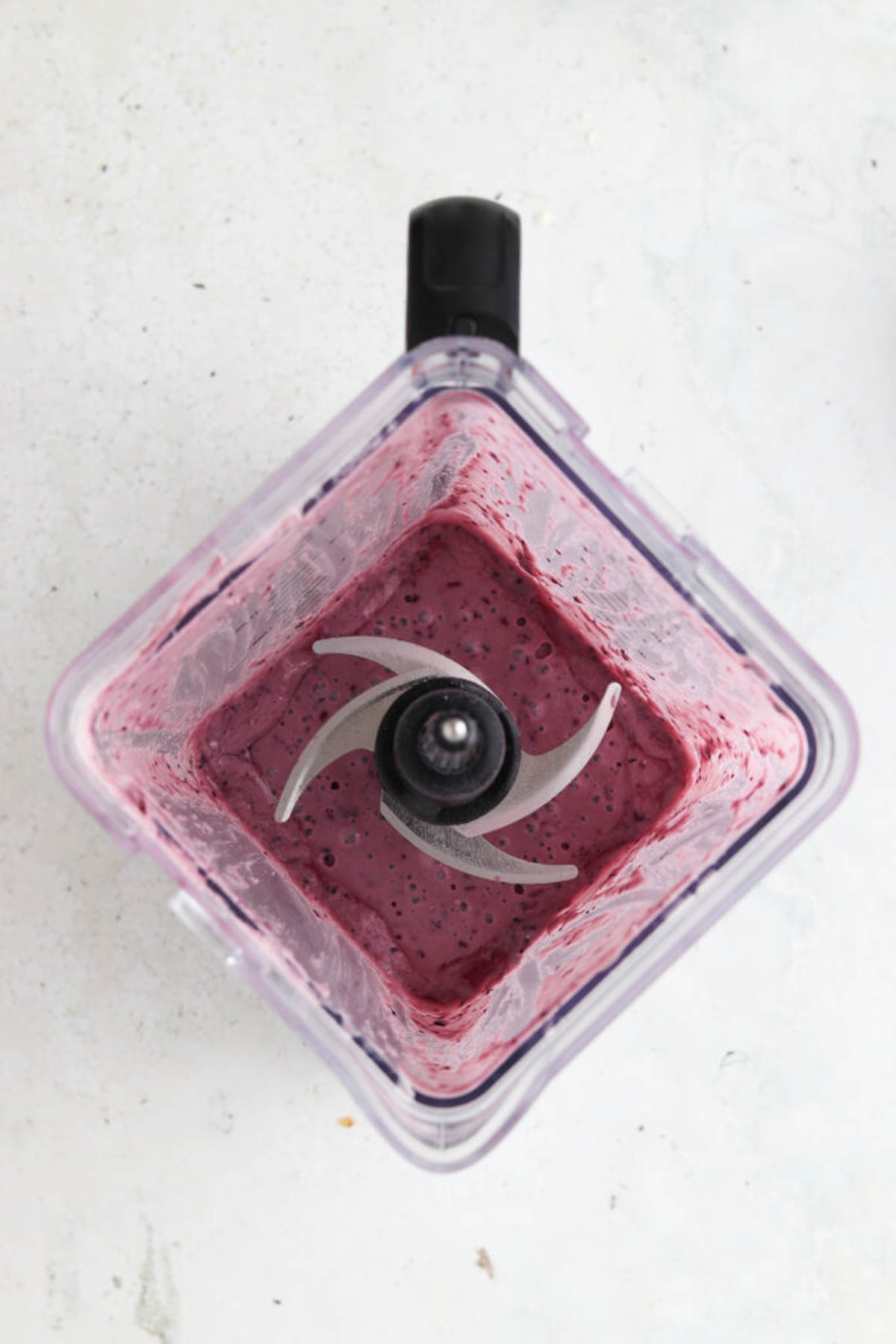 Strawberry blueberry smoothie ingredients blended together in a blender base.