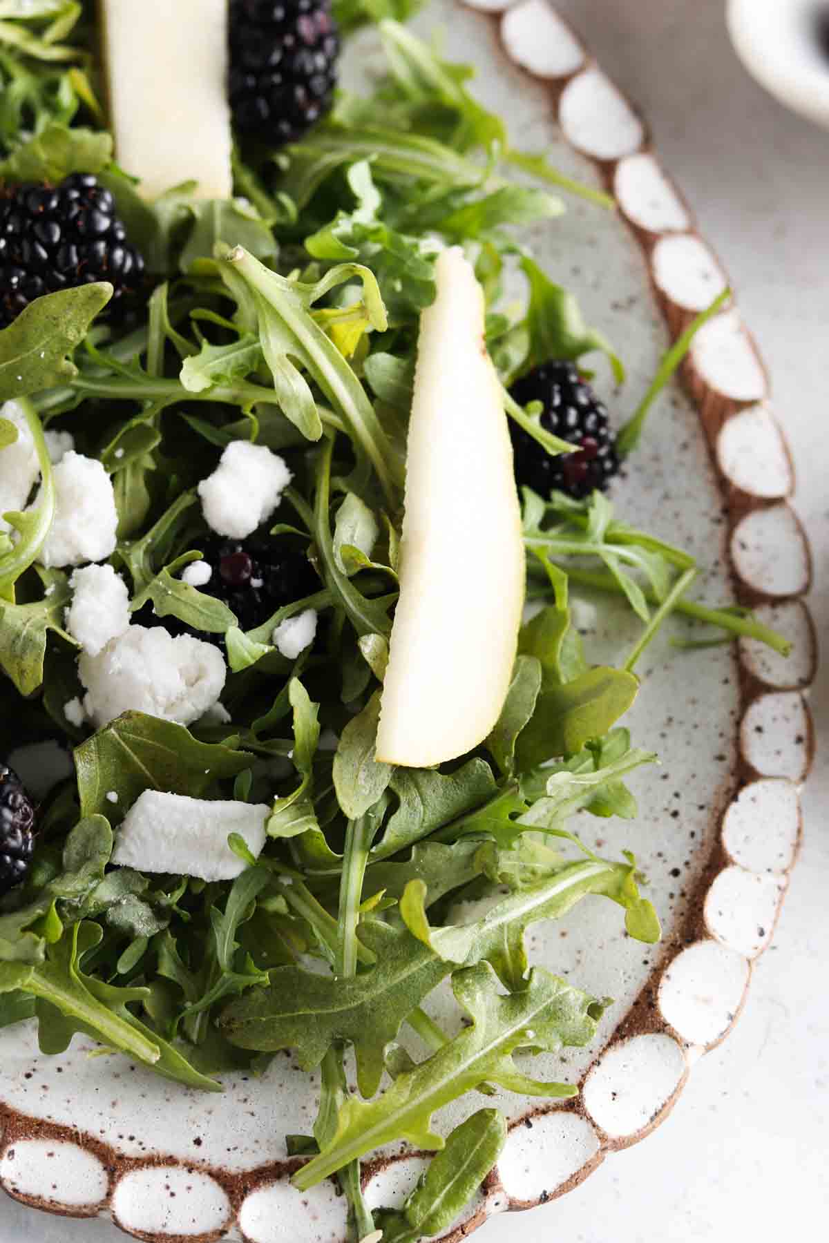 Arugula salad on a plate with pears, goat cheese, sunflower seeds and pomegranate. 