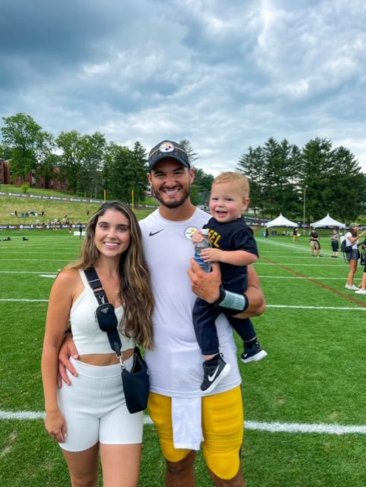 Hillary and Mitch Trubisky on the field at Steeler's training camp with their son. 