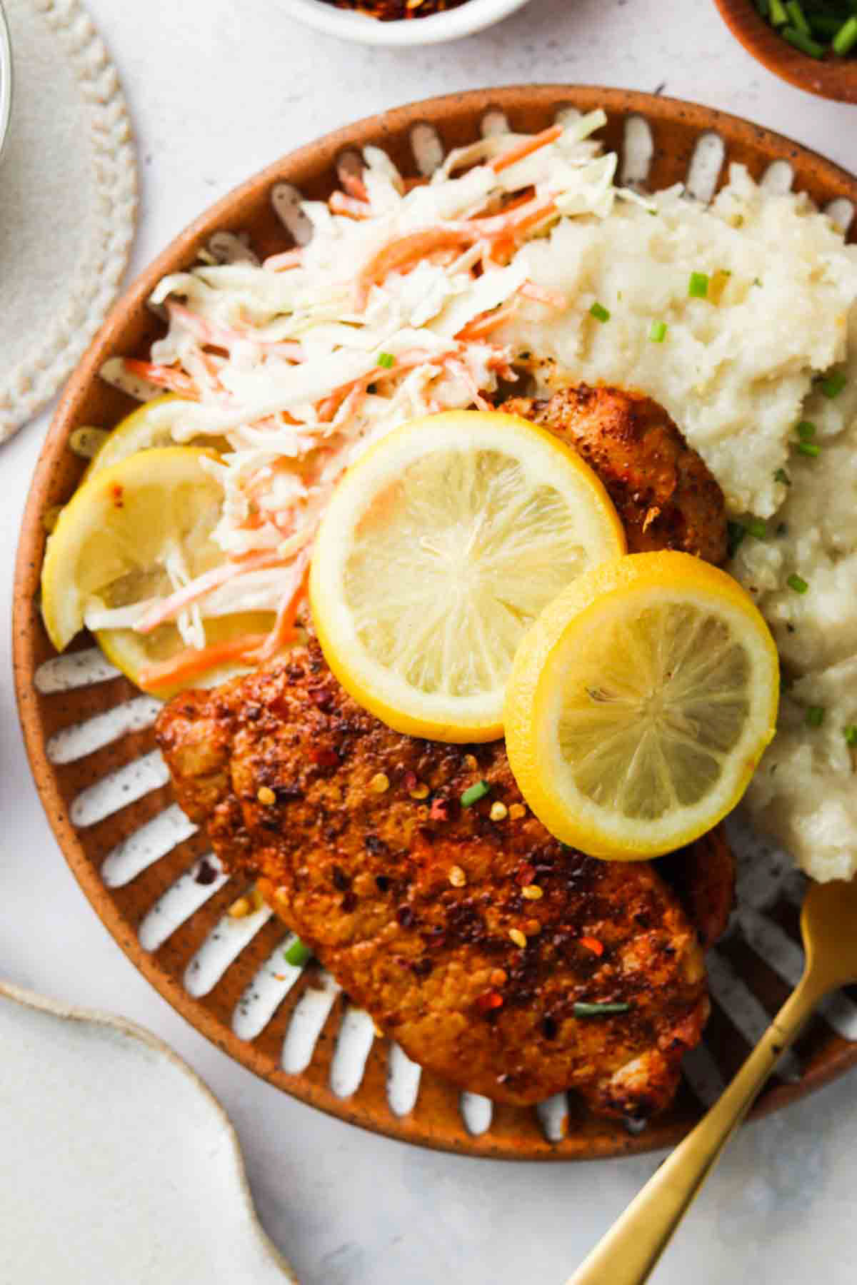 Blackened pork on a plate with lemons and mashed potatoes.