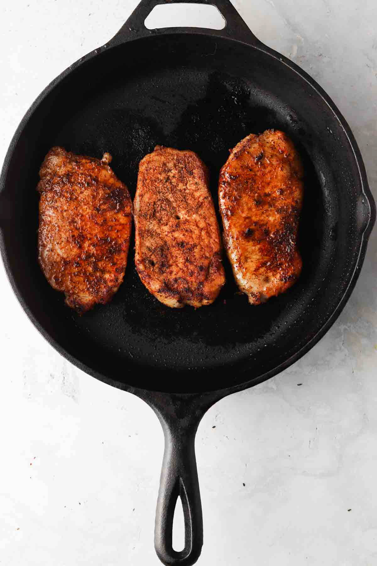 Blackened pork chops in a cast iron pan.