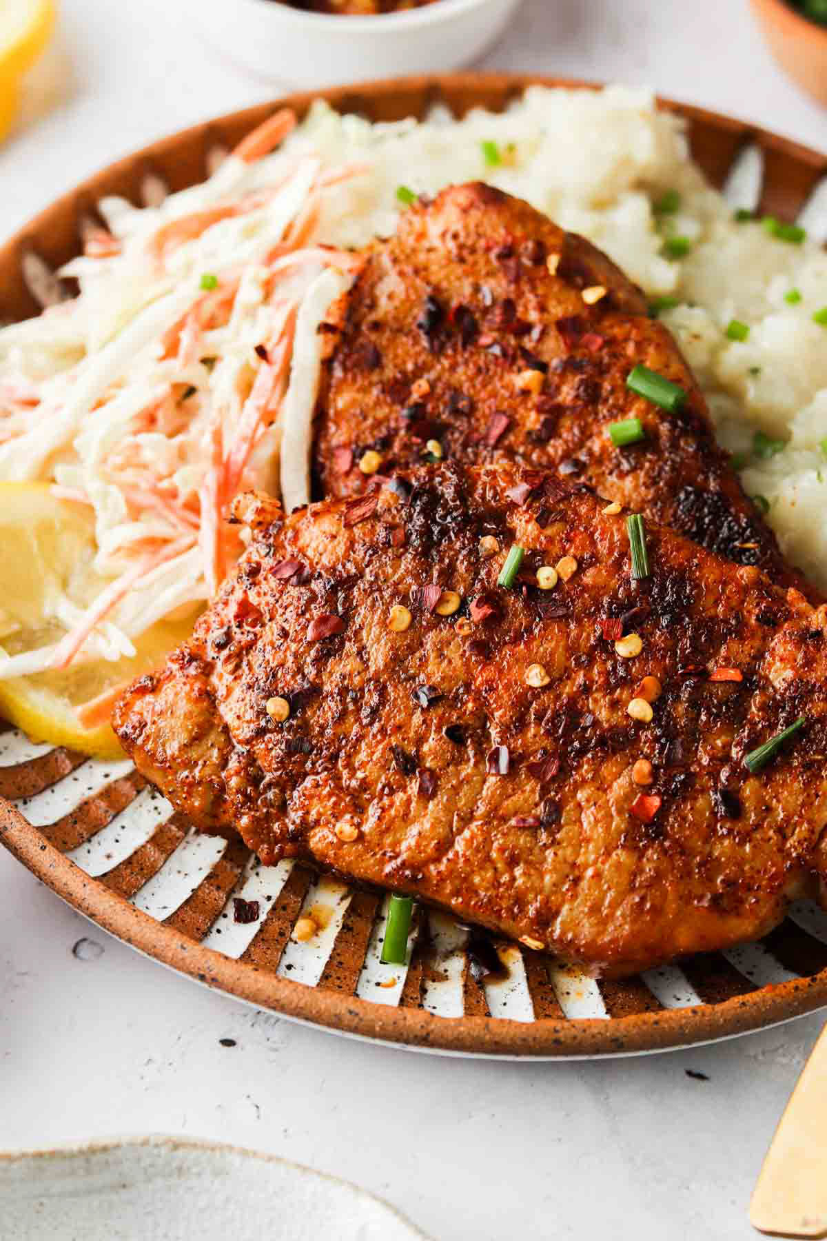 Blackened pork chops on a plate with coleslaw.