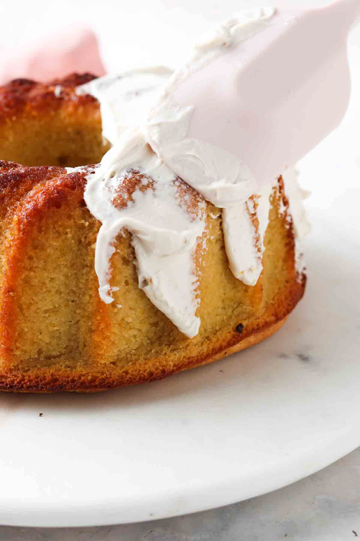 Pink spatula frosting the cake.