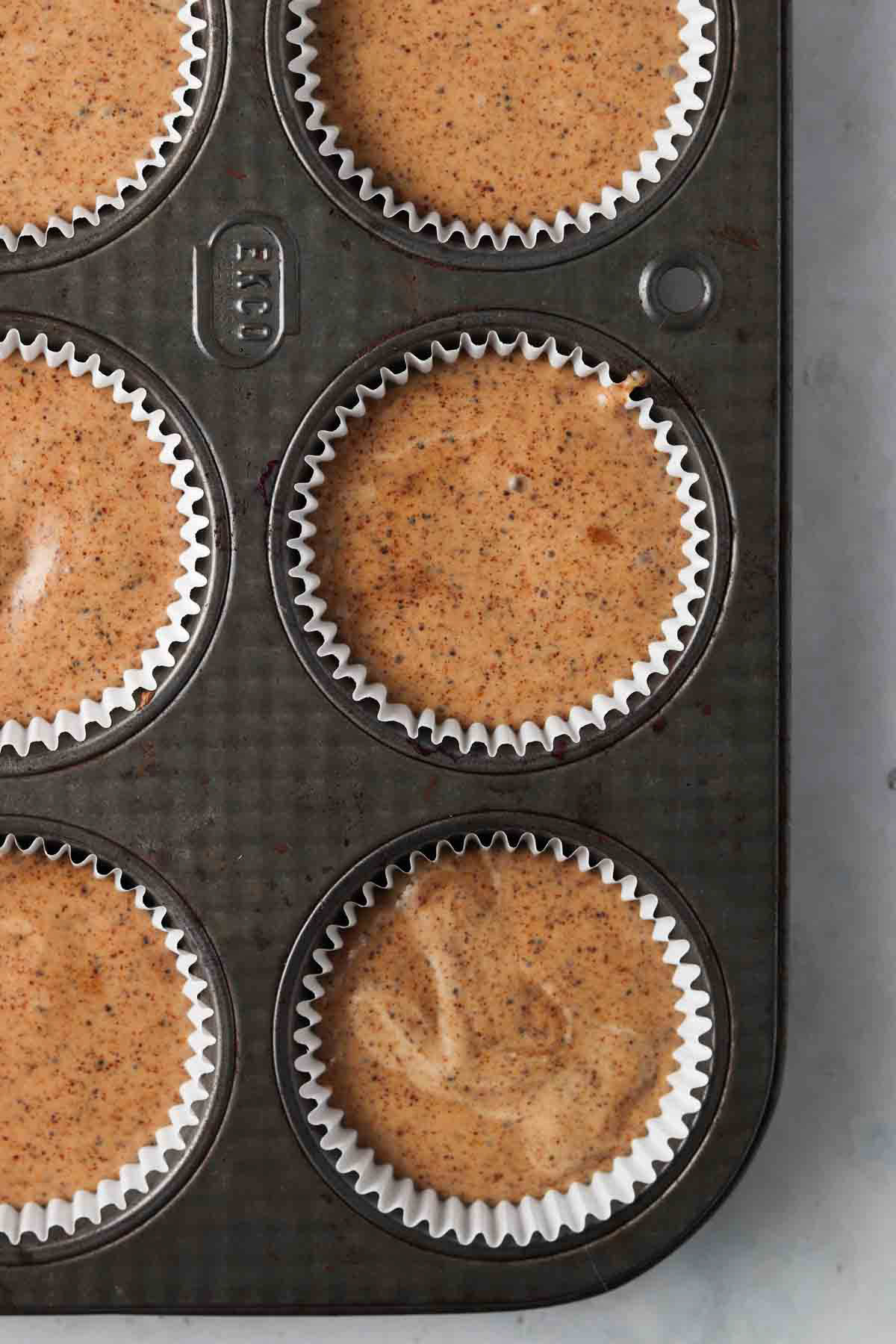 Lemon poppyseed muffin batter in a cupcake pan.