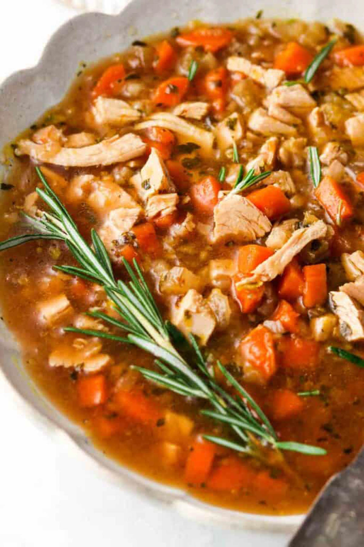 Instant pot turkey soup in a bowl with fresh rosemary.