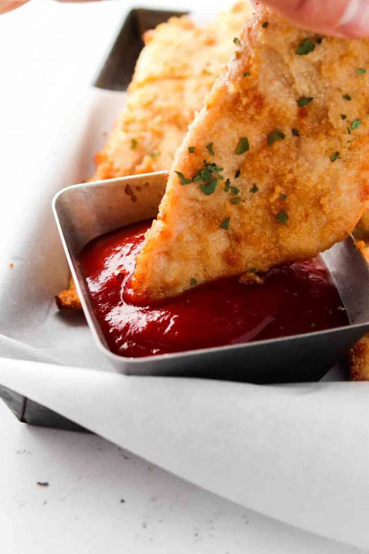 Homemade keto chicken tender being dipped in sauce.