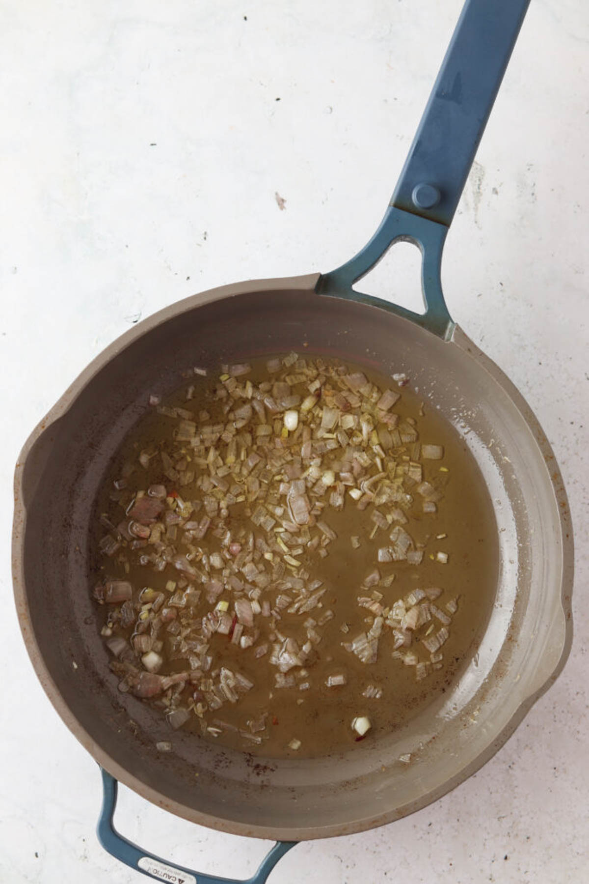 Fresh scallions cooking in a pan with melted ghee. 