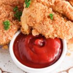 Close up picture of crispy chicken on a white scalloped plate.