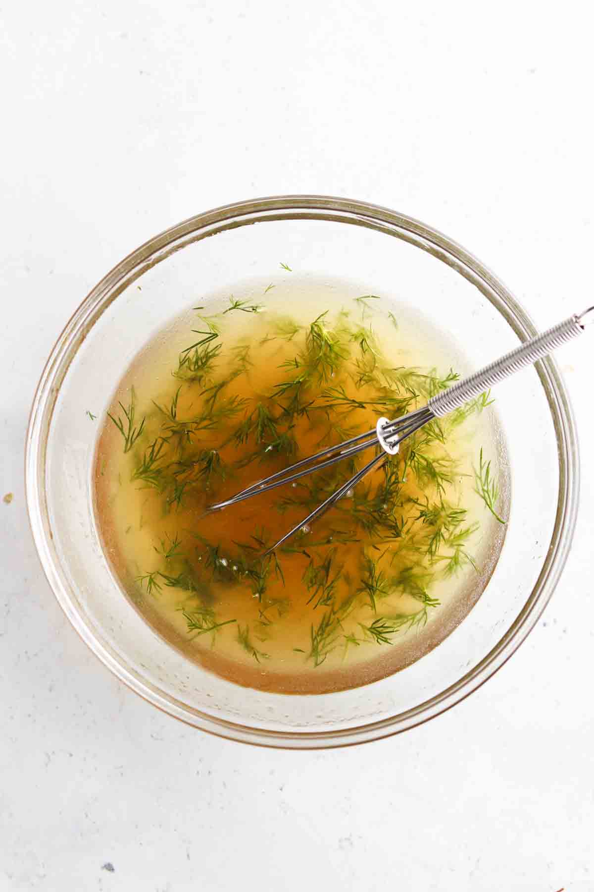 Dressing mixed in a bowl with a small whisk.