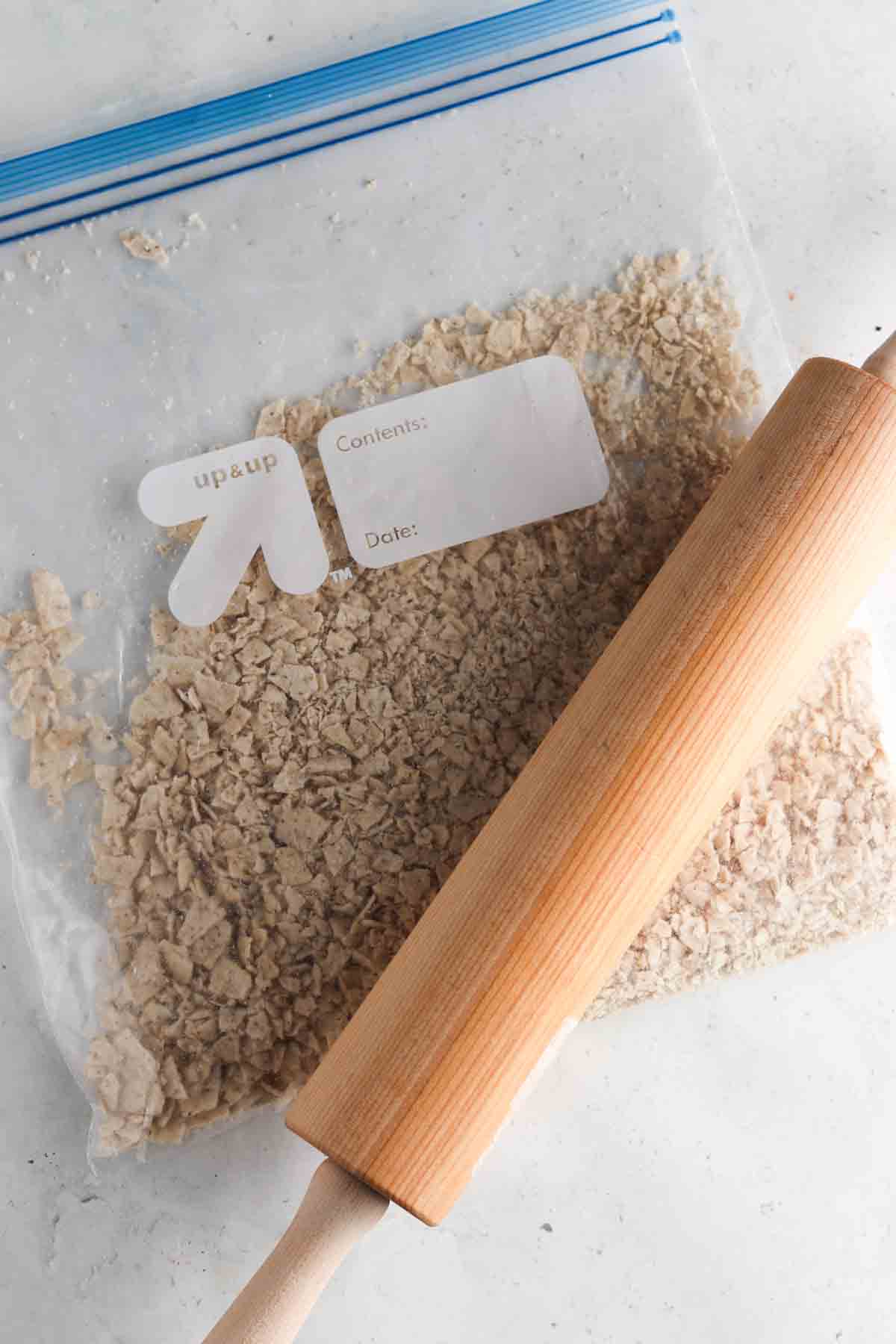 Crushed up chips in a bag with cassava flour being rolled out with a rolling pin.