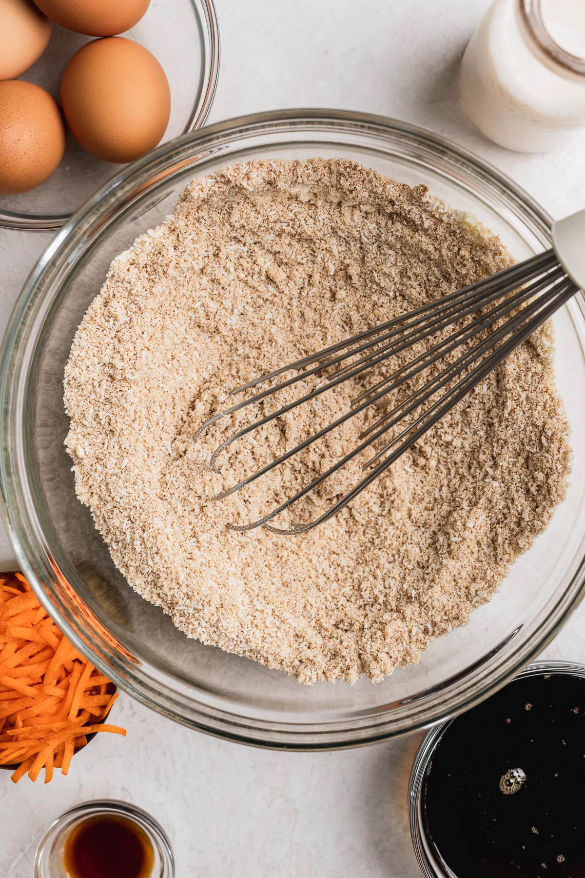 Carrot cake dry ingredients mixed in a bowl with a whisk.