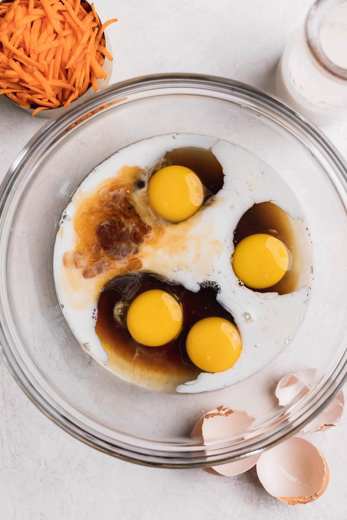 Eggs, maple syrup, almond milk, and vanilla in a glass bowl. 