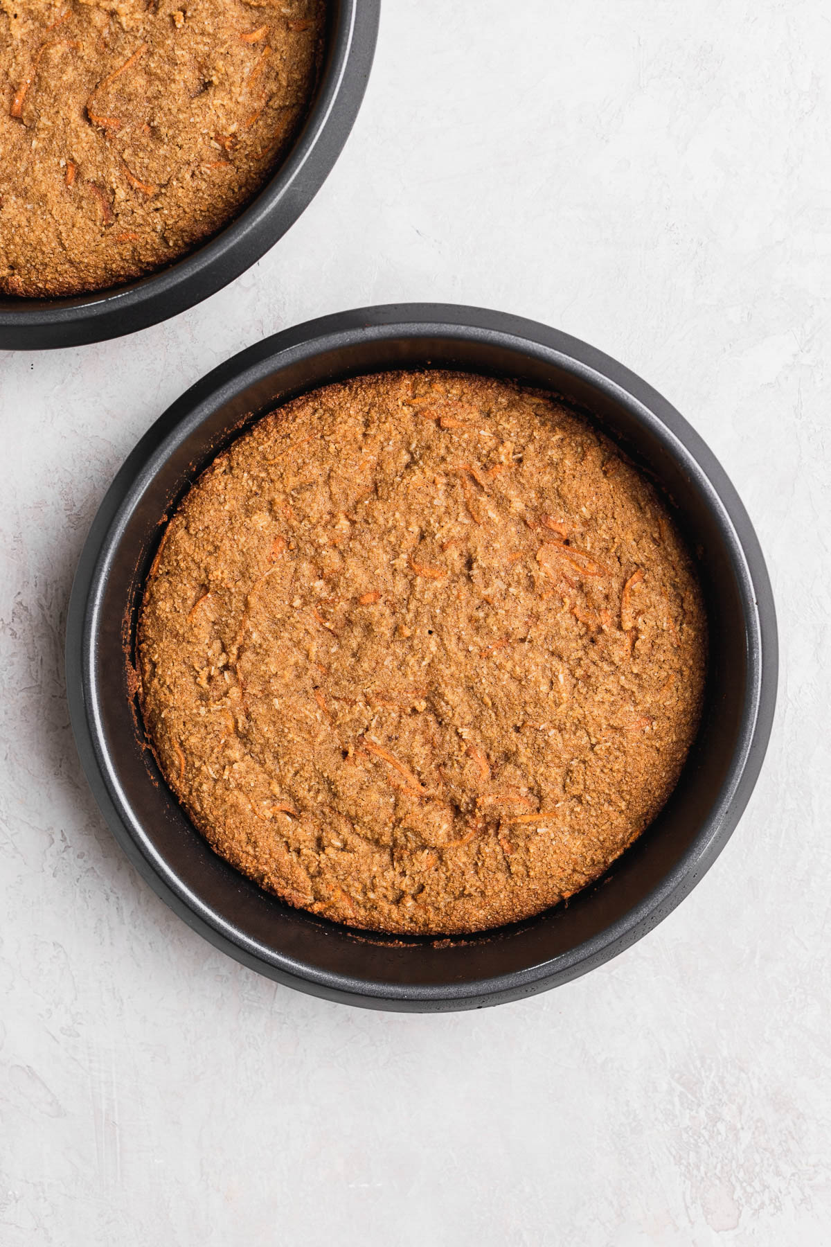 Cooked round carrot cake in an 8 inch cake pan.