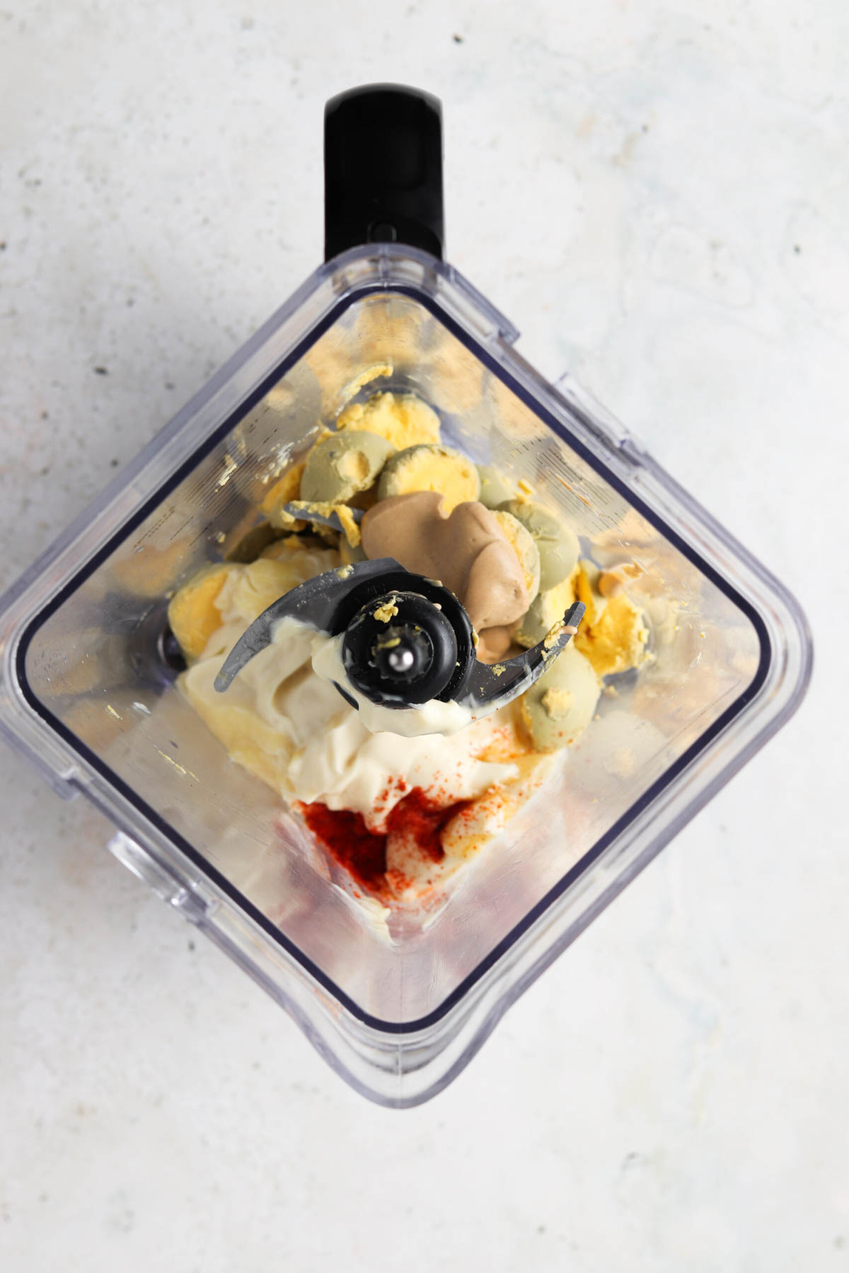 Egg yolks, avocado mayo, pickle juice and paprika inside a food processor. 