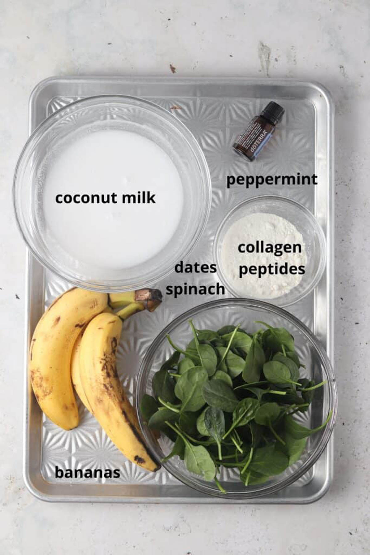 Mint smoothie ingredients in small glass bowls on a silver tray. 