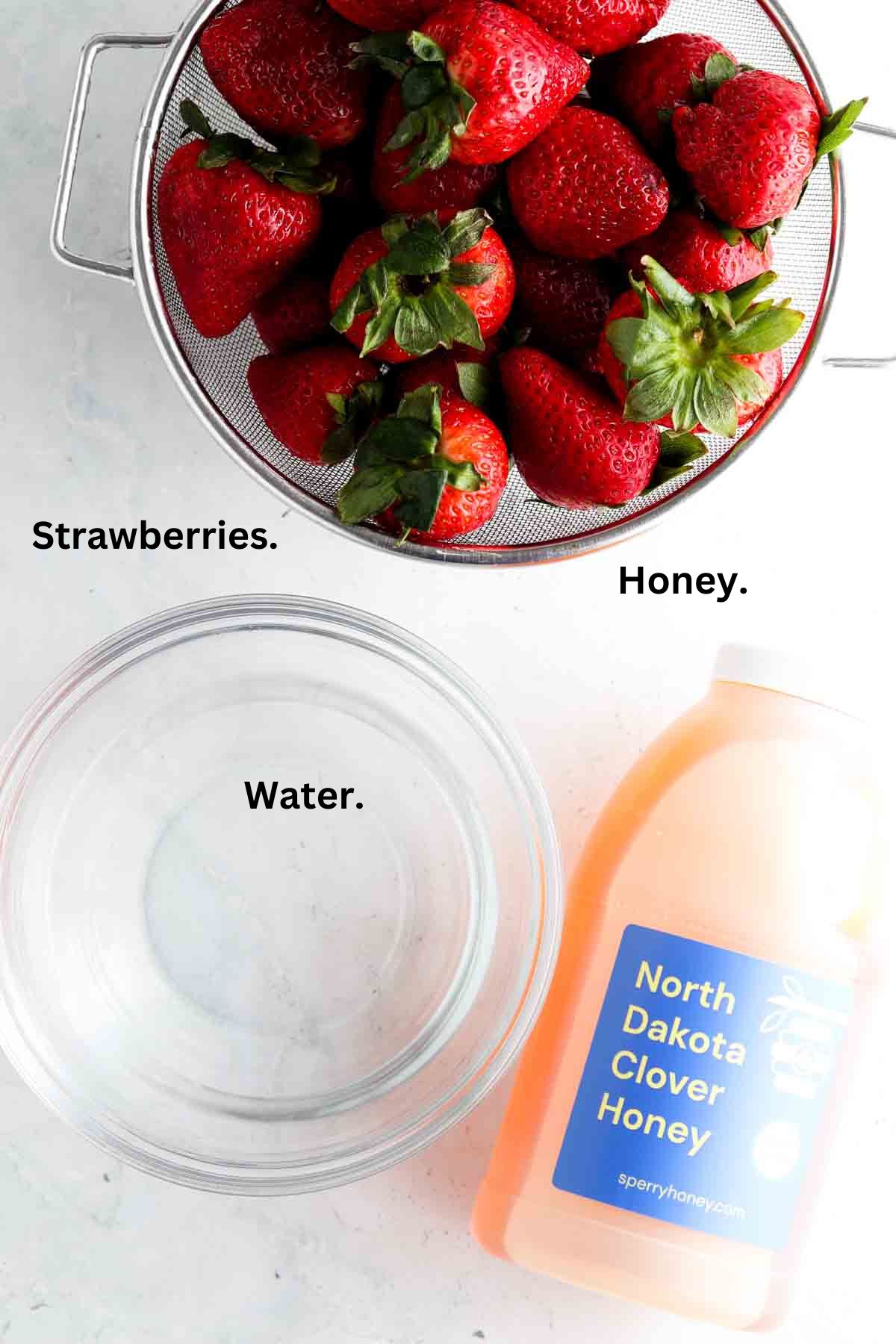 Strawberry simple syrup ingredients laid out on the counter top in bowls.