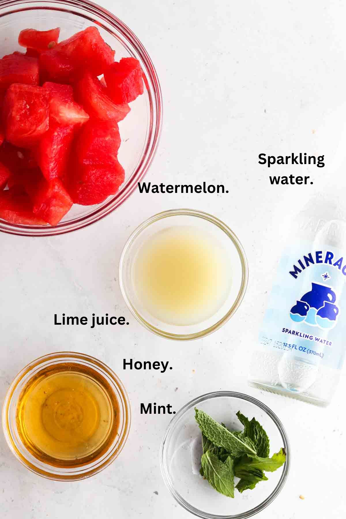 Picture of watermelon mocktail ingredients laid out on the counter in bowls.