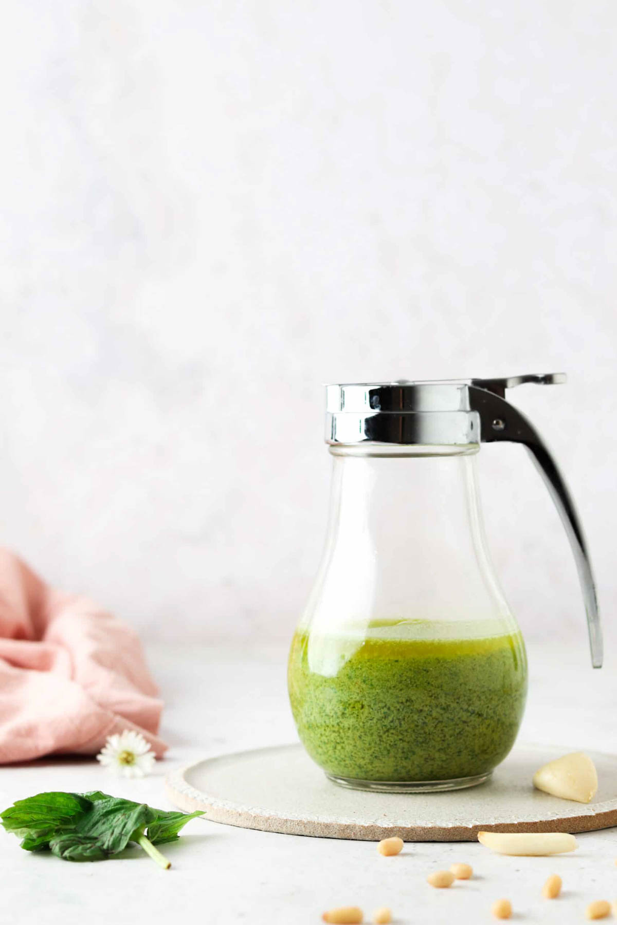 Fresh whole30 pesto in a jar surrounded by fresh garlic and basil. 