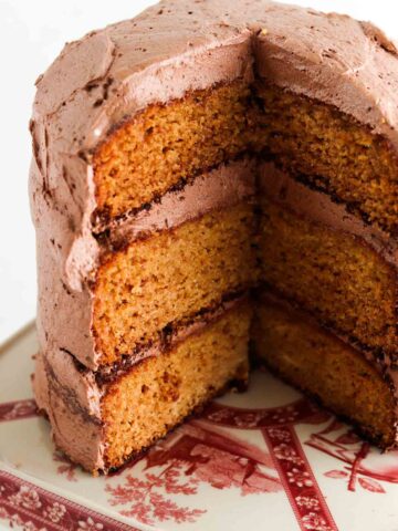 3 layered cake with chocolate frosting on a cake platter.