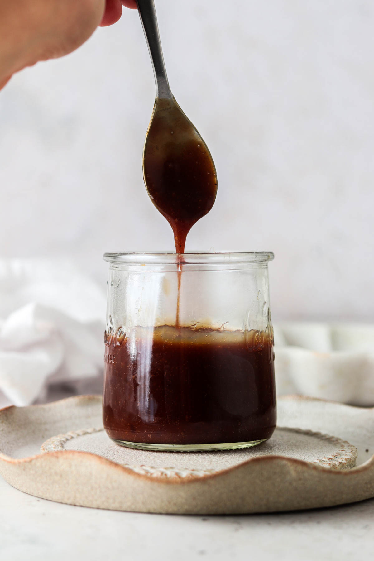 Vegan caramel sauce in a jar with a spoon.