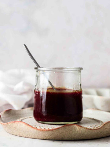 Vegan caramel sauce in a glass jar with a spoon in it.