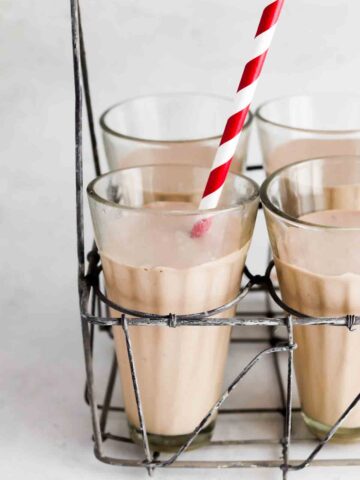 Close up photo of a milkshake in a milkshake glass with a red straw.