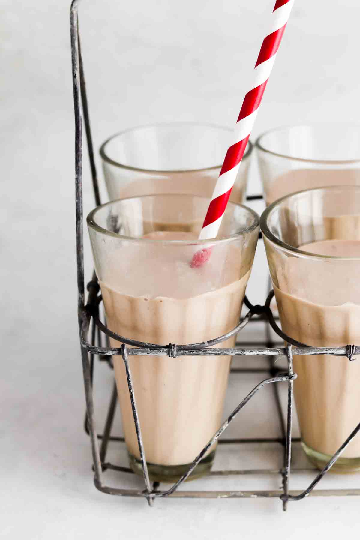 Picture of a chocolate milkshake in a cup with a red and white straw. 