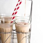 A chocolate milkshake being poured into a glass.