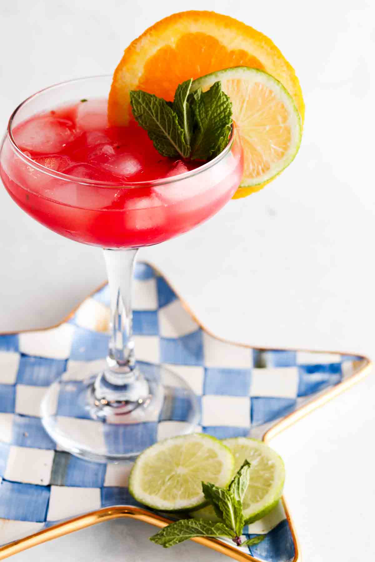 Watermelon mocktail margarita in a margarita glass with a lime and orange on top.