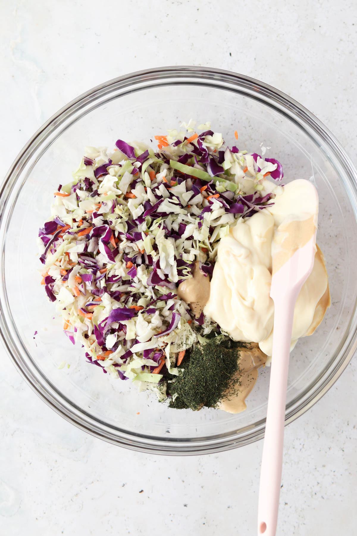 Gluten free coleslaw ingredients in a large glass bowl unmixed.