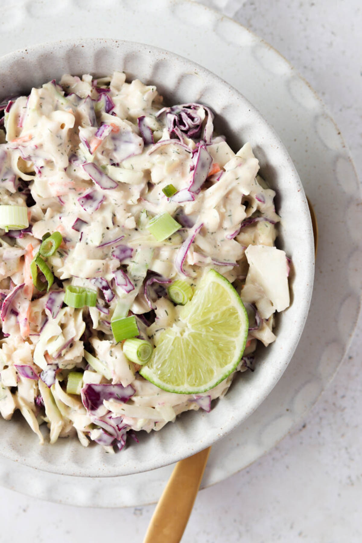 Gluten free coleslaw in a clay bowl with a fresh lime slice. 