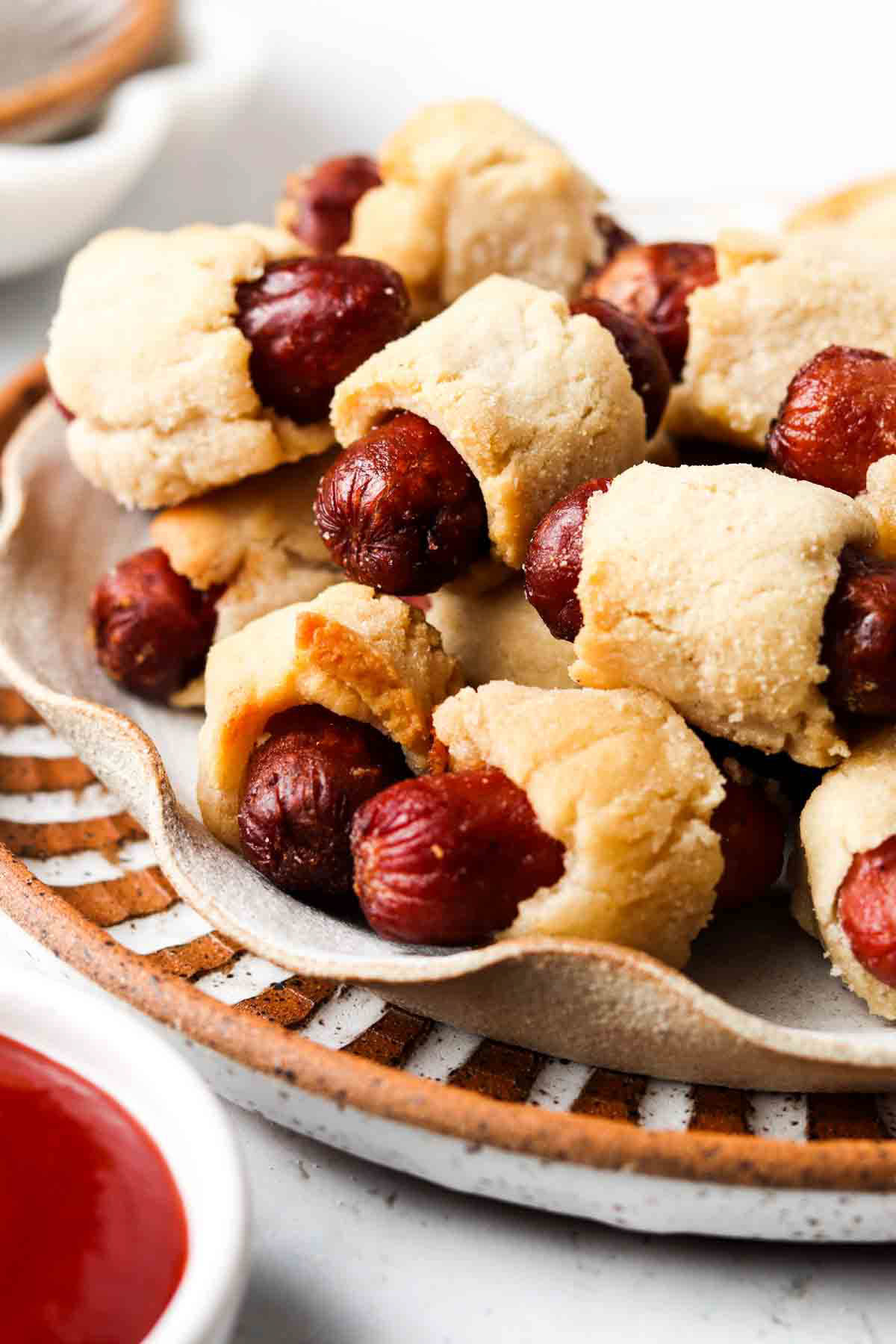 Gluten free pigs in a blanket piled on a plate.