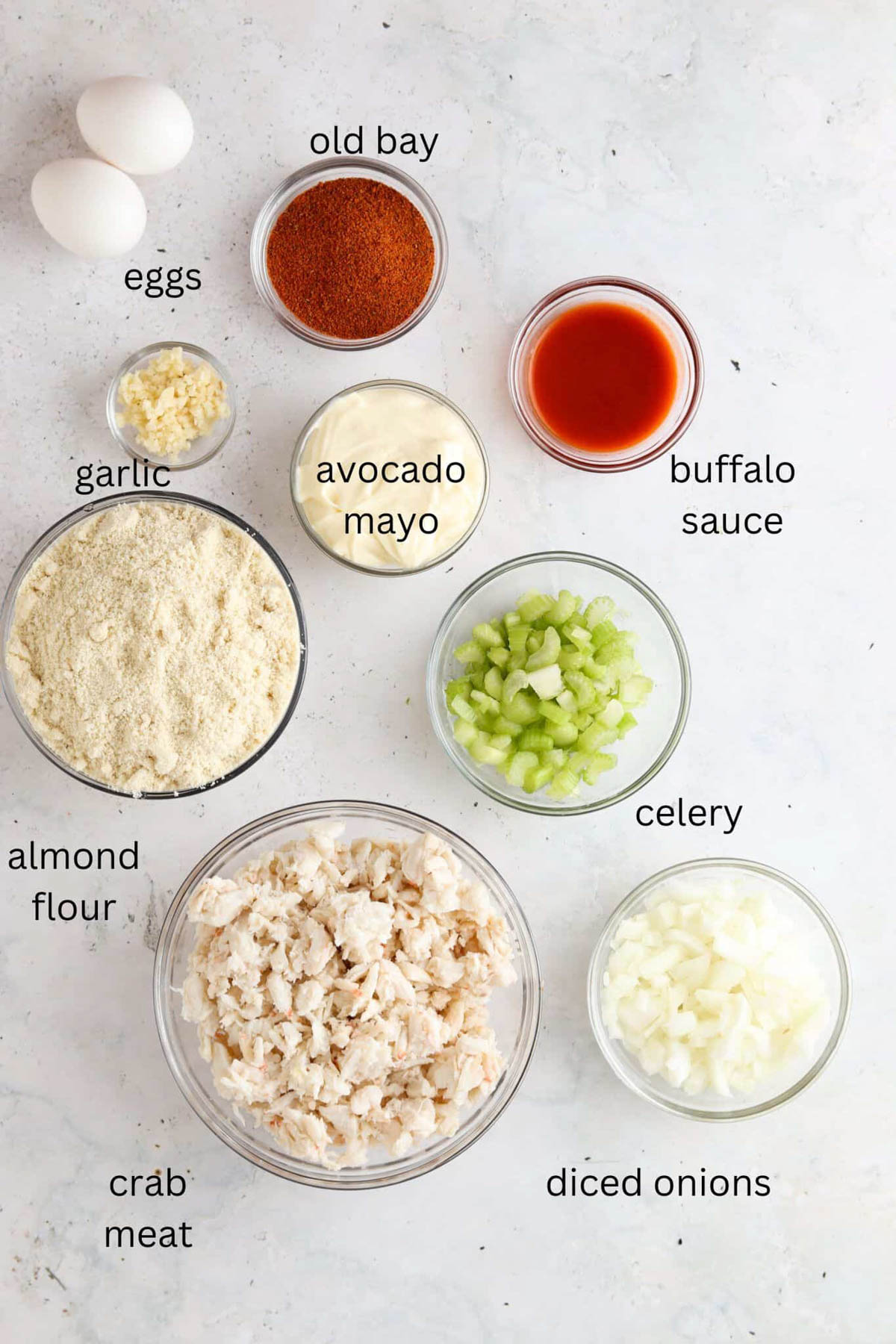 Crab cake ingredients laid out in small glass bowls on the counter. 