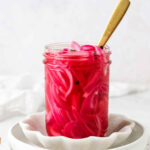 Mexican pickled onions in a mason jar with a gold spoon.