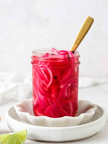 Mexican pickled onions in a mason jar with a gold spoon.