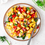 Pineapple pico de gallo on a plate with a silver spoon.