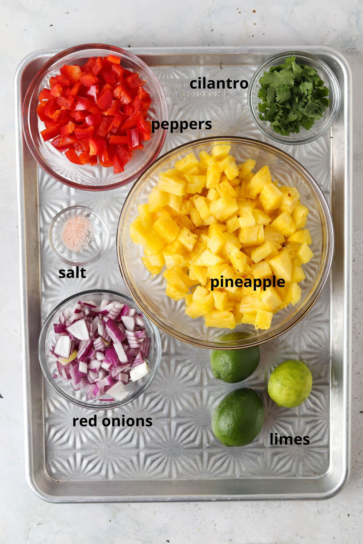 Pineapple pico de gallo ingredients in glass bowls on a silver platter. 