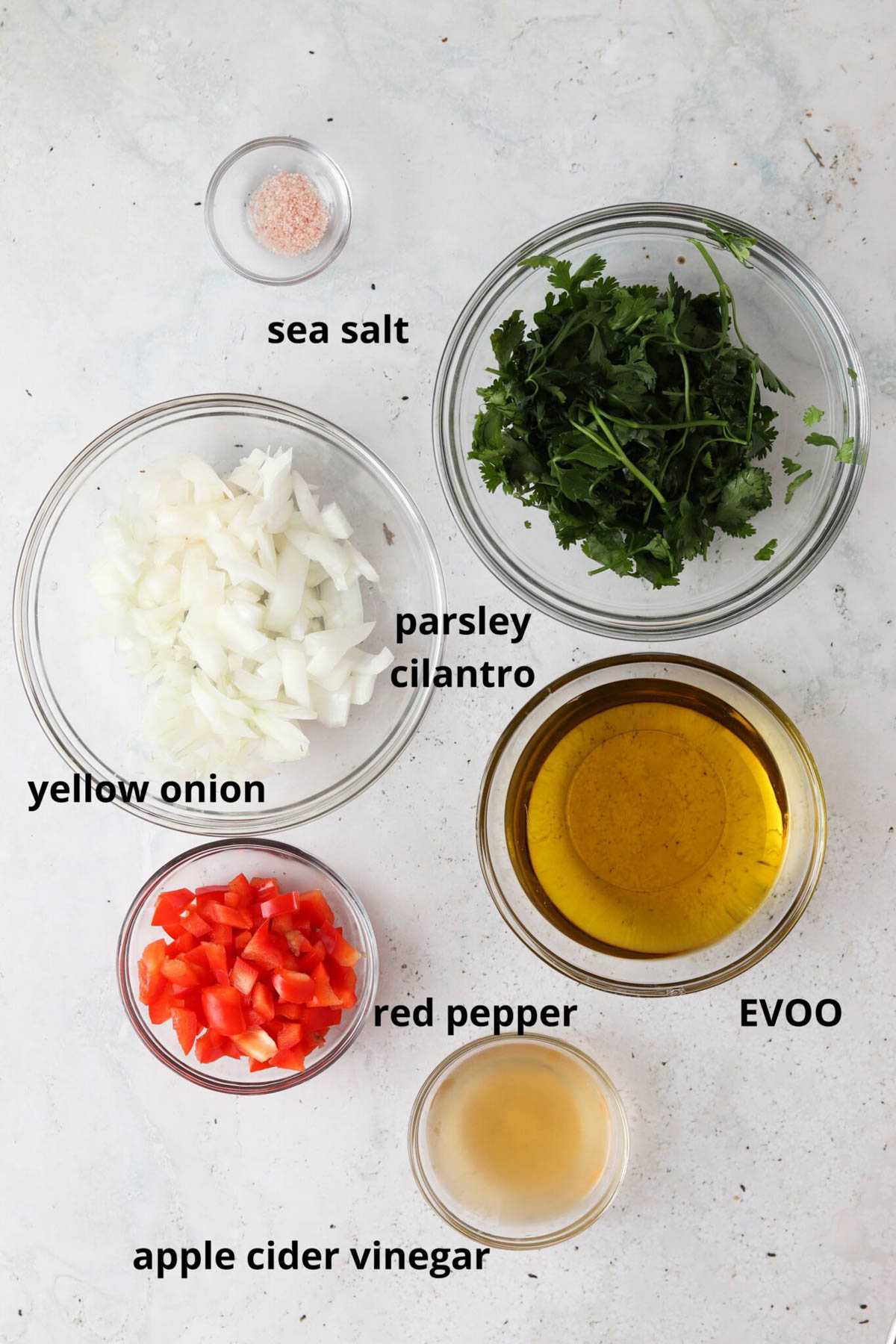 Red chimichurri sauce ingredients in small glass bowls.