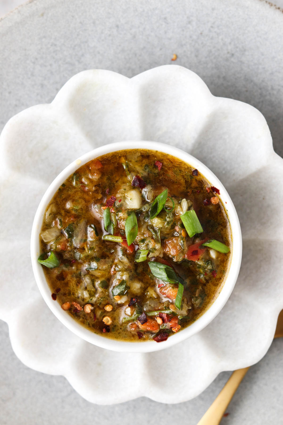 Red chimichurri sauce in a small bowl with red pepper flakes.
