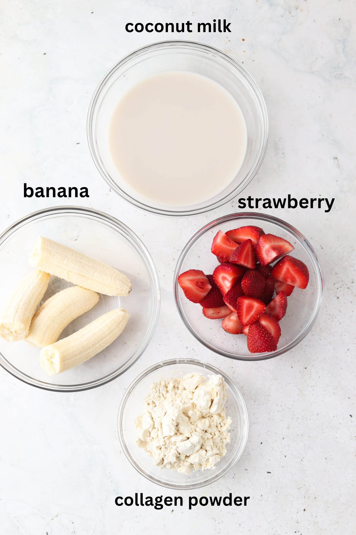 Strawberry banana smoothie bowl ingredients in small glass bowls. 