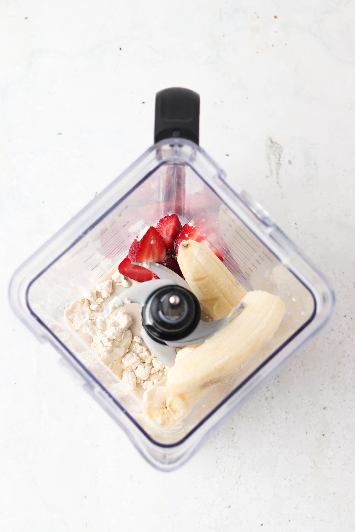 Strawberries, bananas, protein powder and milk in a blender. 