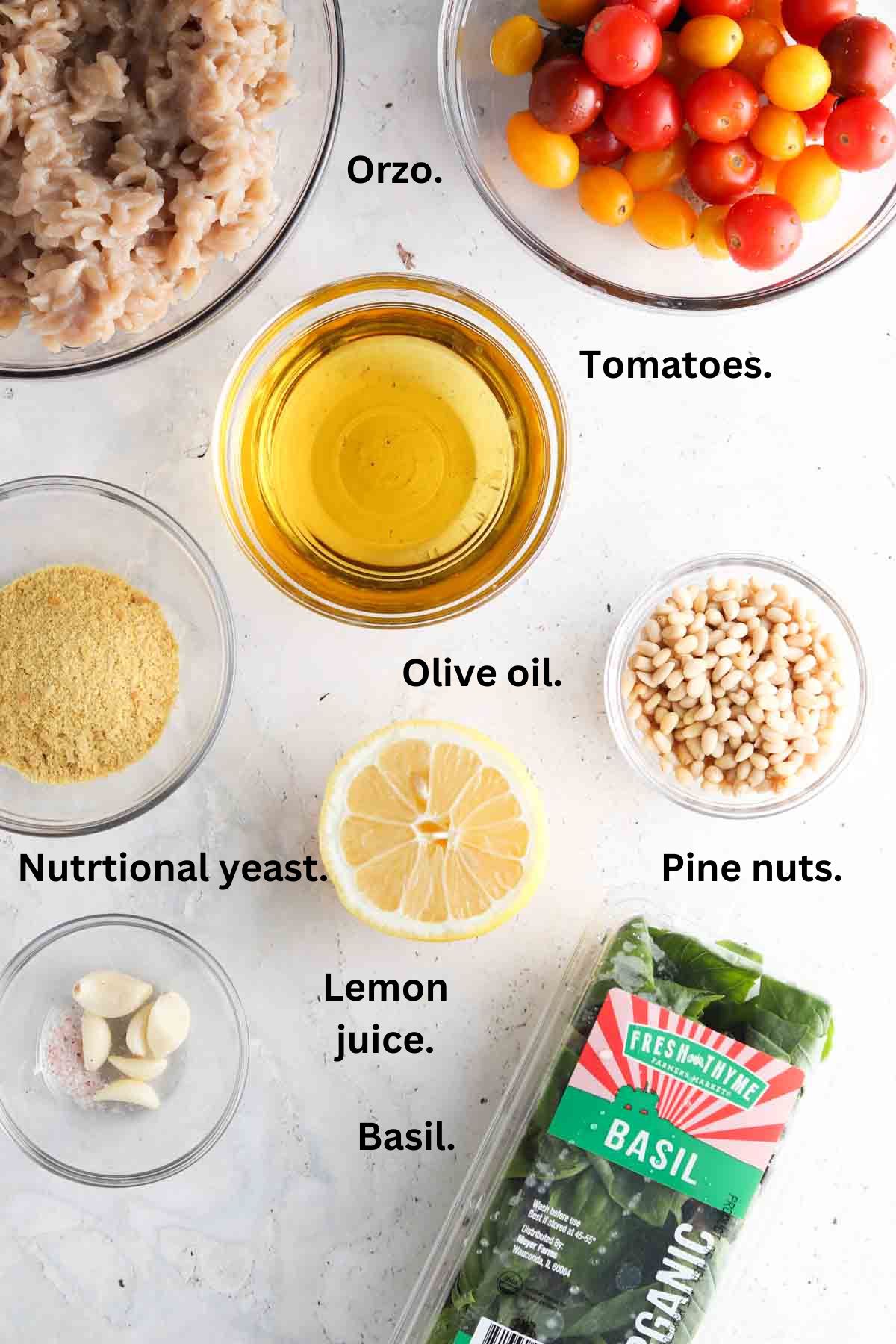 Orzo pesto salad ingredients all laid out on the counter top in glass bowls.