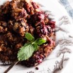 Blackberry crisp on a plate with a fork and blue linen towel next to it.