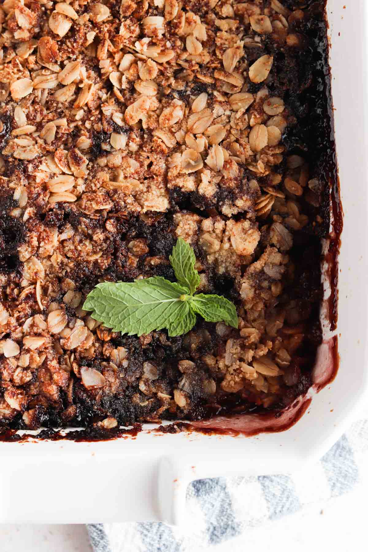 Blackberry crisp on a casserole baking dish with fresh mint on top.