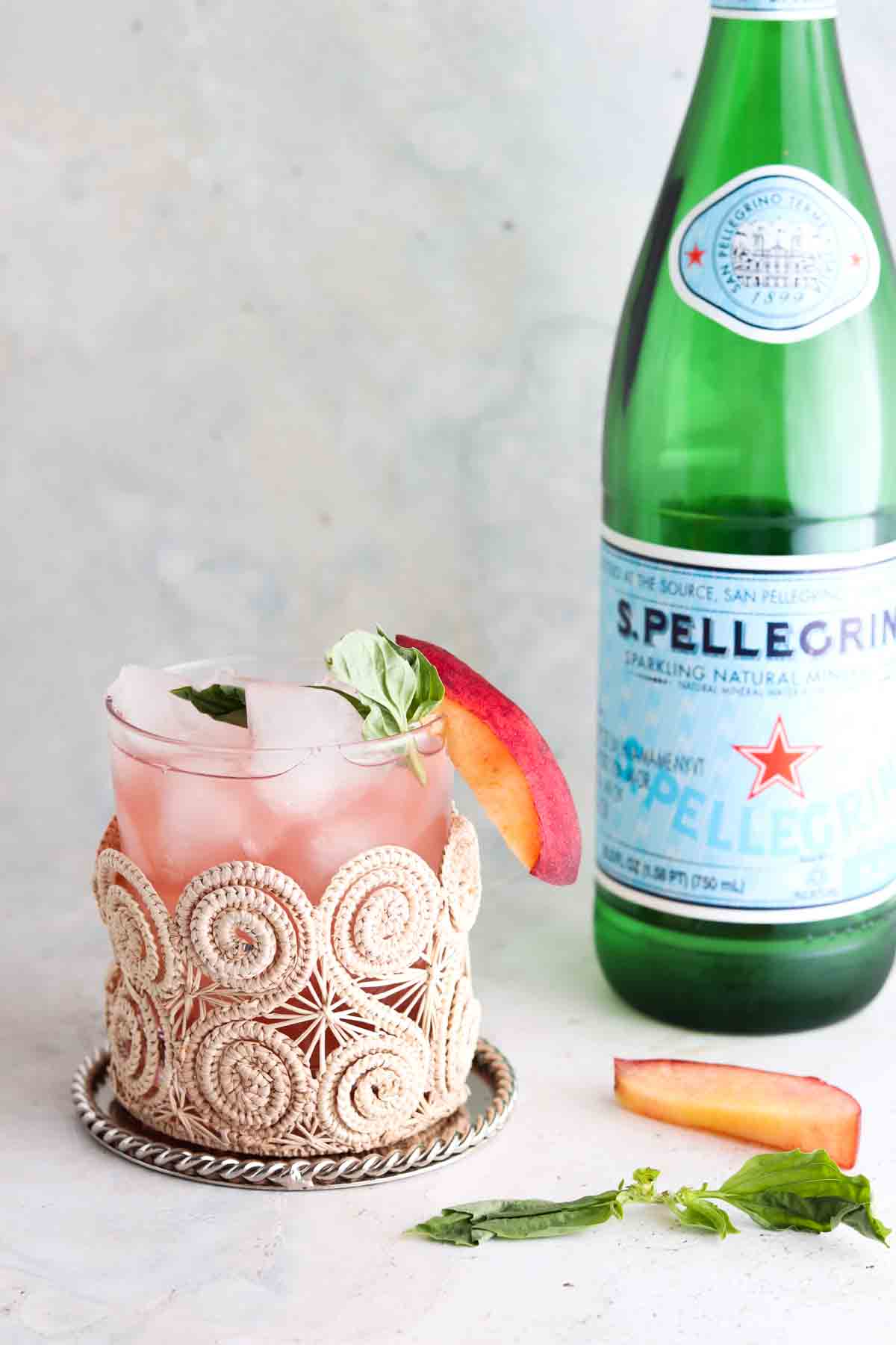Peach mocktail in a cup with fresh basil on top.