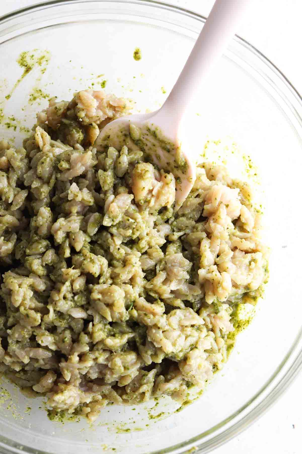 Pesto and orzo mixed in a bowl.