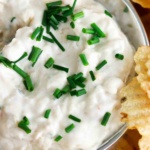 Creamy white dip in a silver container with fresh chives on top.