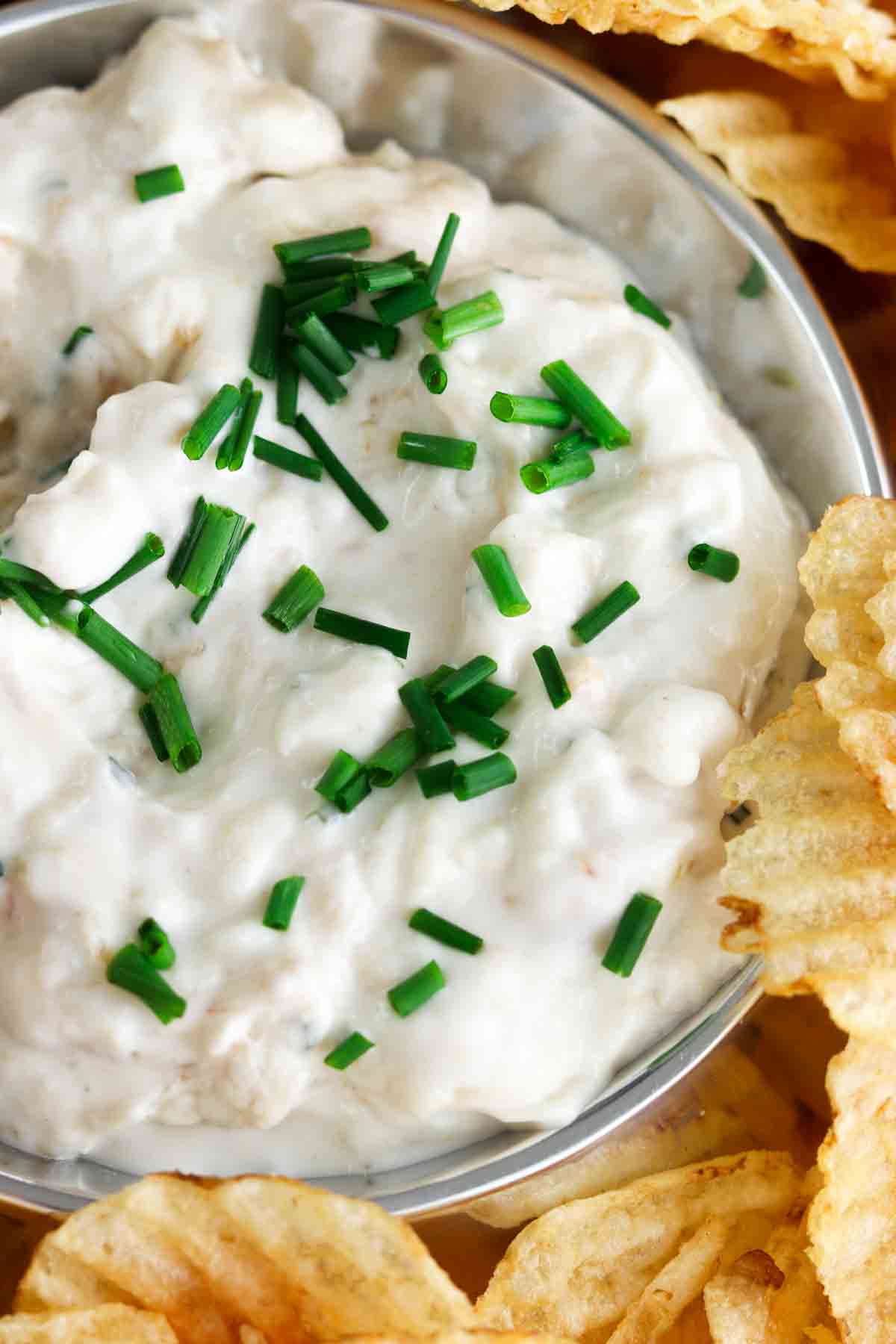 Creamy white dip in a silver container with fresh chives on top.
