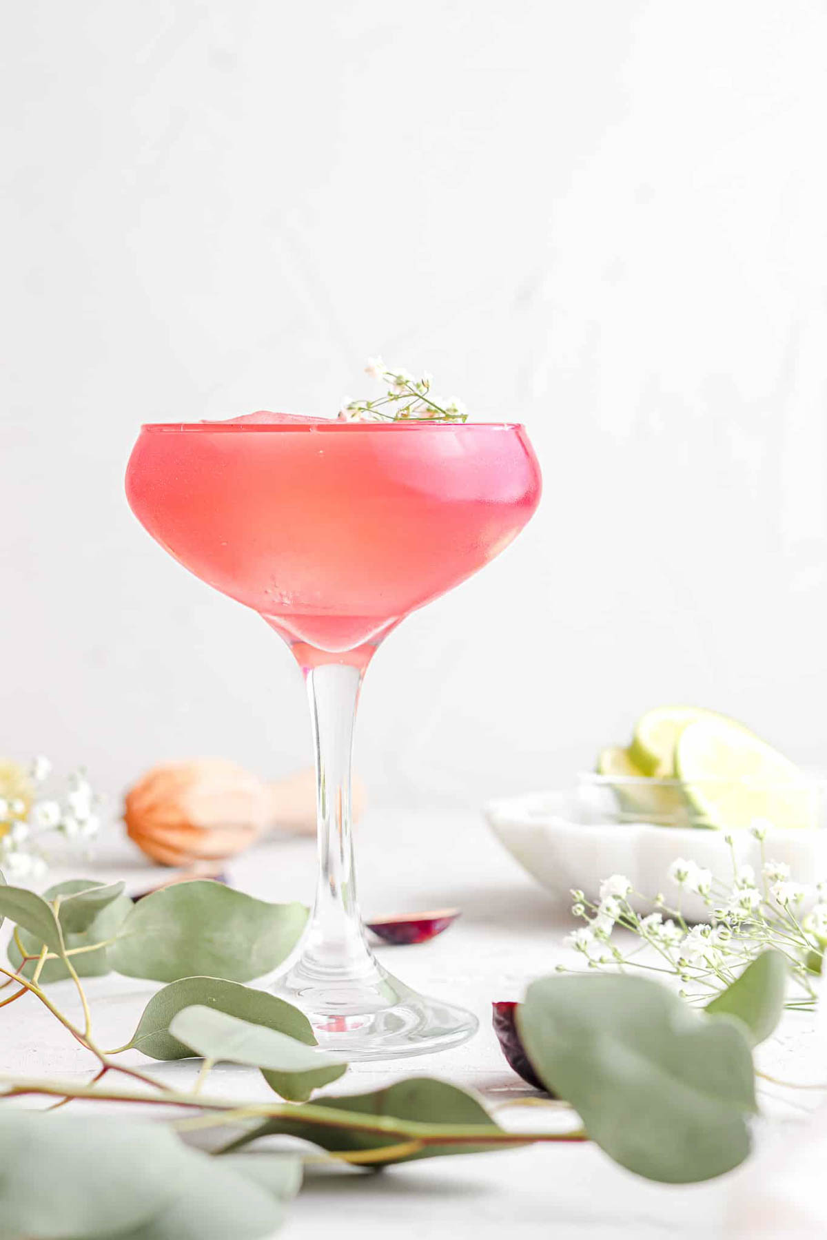 Fig simple syrup in a glass garnished with fresh flowers and lime.