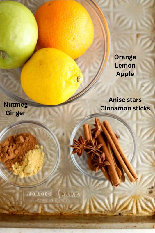 Lemons, oranges, apples, cinnamon and nutmeg in small bowls laying out.